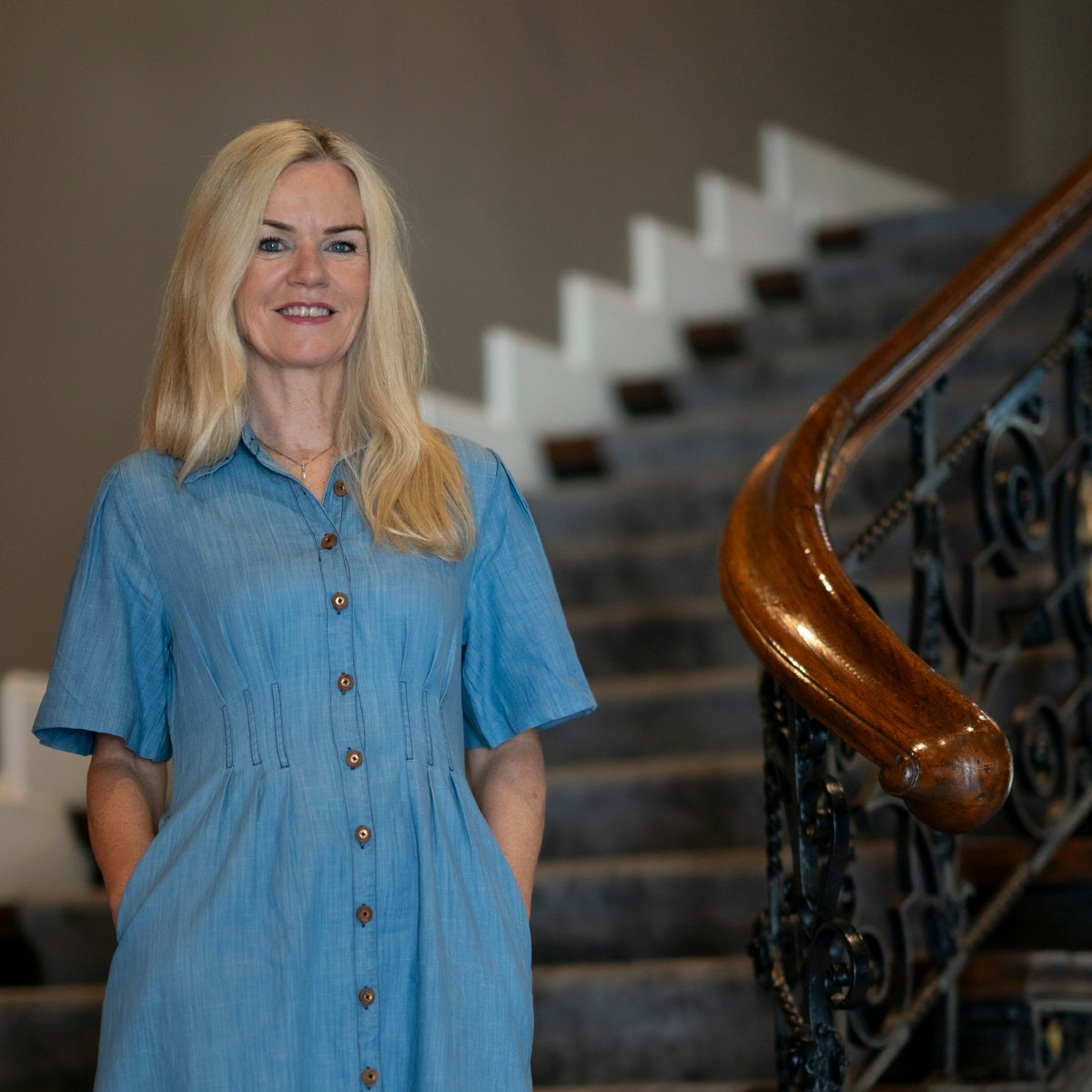 Modell i lys blå denimkjole med kort erm og feminin passform i sommersol